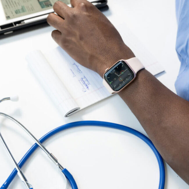 Healthcare professional writing notes with a stethoscope on the table