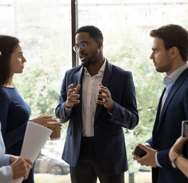 Group of diverse professionals engaged in a discussion near a window.