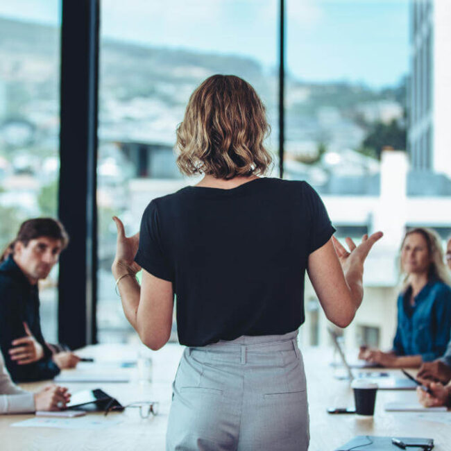 Businesswoman leading a meeting with a group of professionals in a conference room.