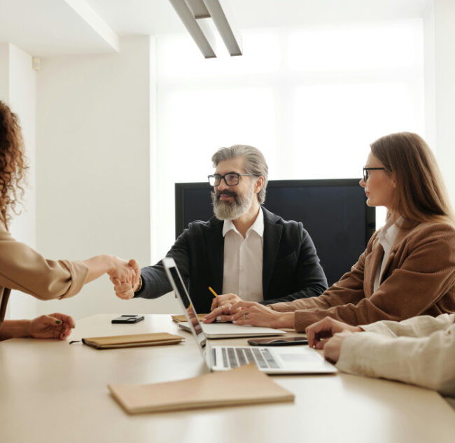 Professionals in a meeting shaking hands across a conference table