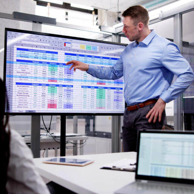 Businessman presenting data on a large screen during a meeting