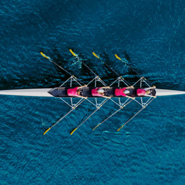 Aerial view of a rowing team working in unison on a boat in the water