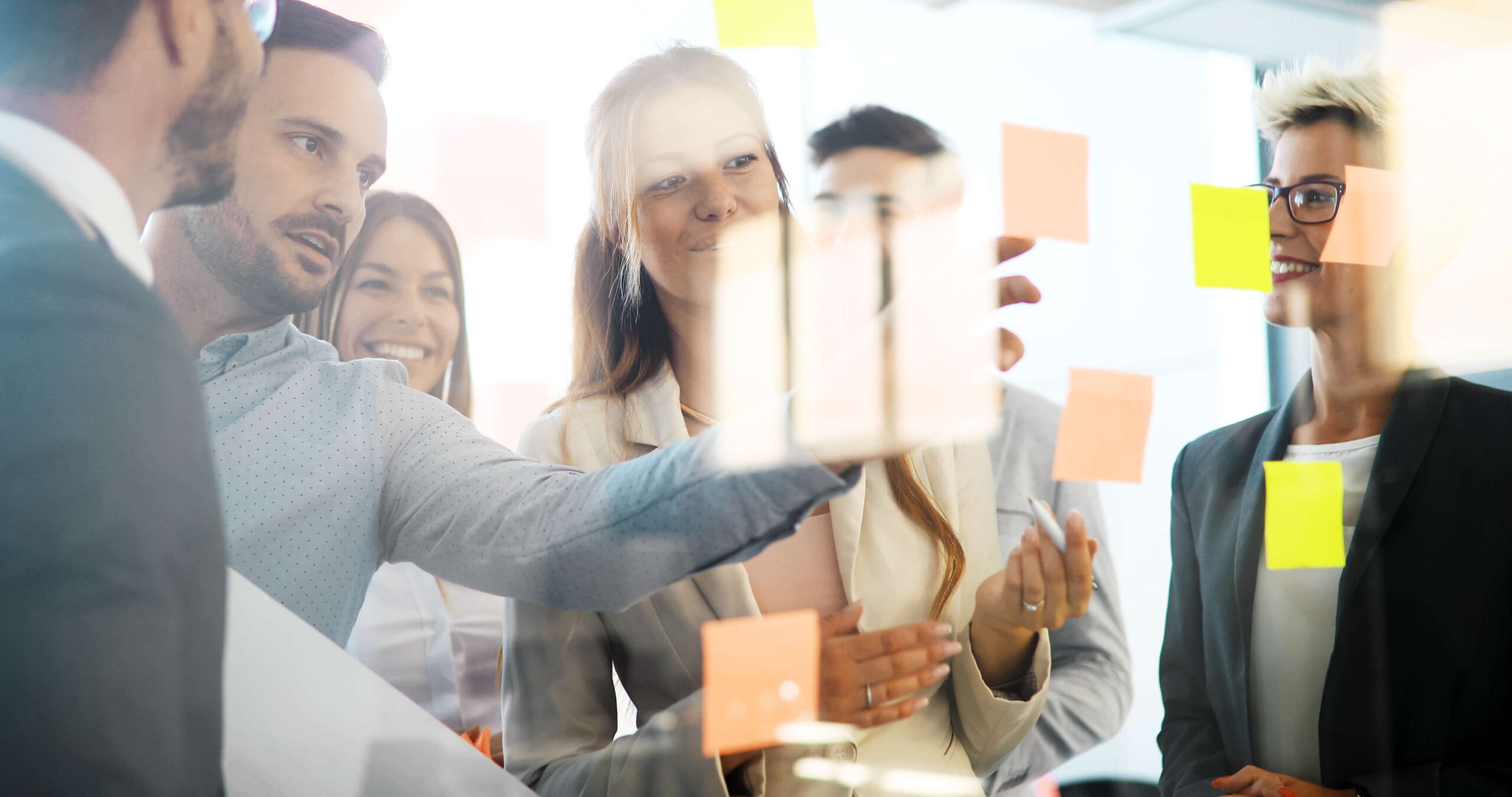 Group of peope standing in front of a glass wall and pinning on post-it's