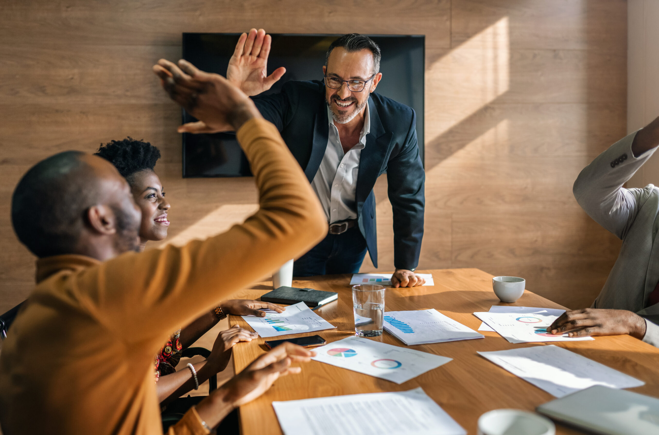 People sitting at a table in a business environment and two people high five