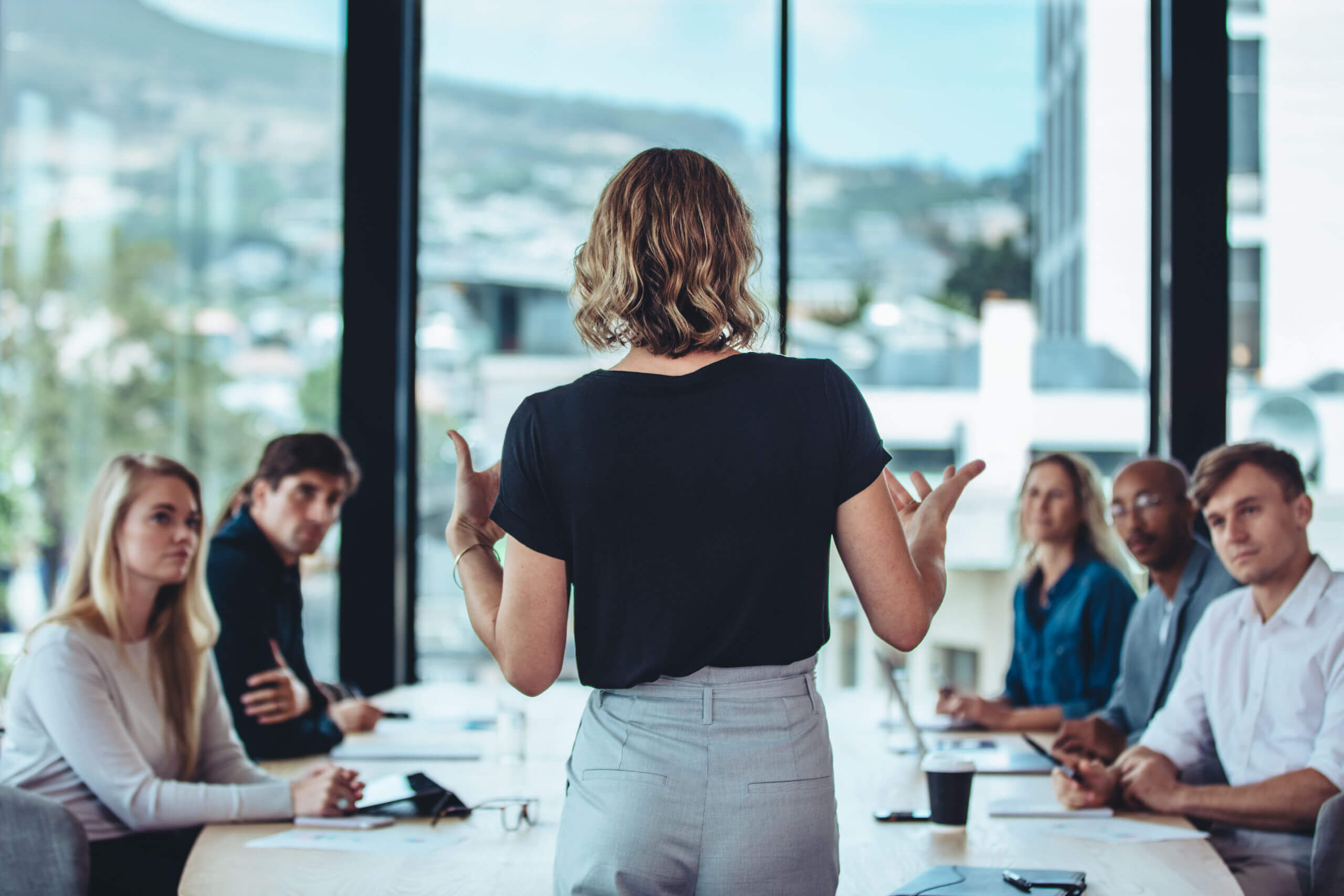 A business meeting with a group of people and a woman presenting