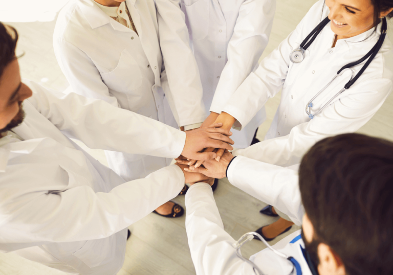 Health care professionals standing in a circle, putting their hands together